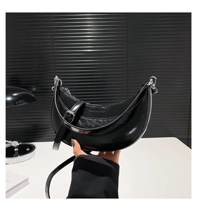 Détail du sac croissant en cuir ciré noir avec ferrures argentées et logo embossé