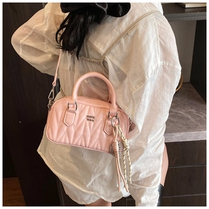 Detail of pink quilted Boston bag with crossbody strap and woven rope charm
