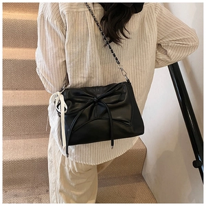 Detail view of black pleated bow shoulder bag with metal chain and silk ribbon decoration