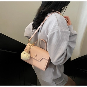 Borsa a tracolla rosa con ciondolo a pompon bianco indossata da una modella