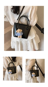 Detail of black glossy bucket bag with a cute bear charm and adjustable shoulder strap