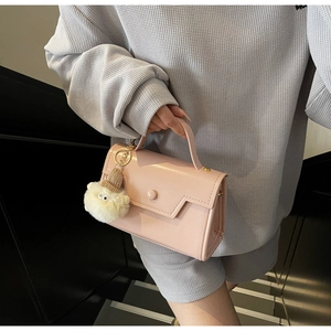 Dettaglio della borsa in pelle rosa con patta geometrica e ciondolo in peluche bianco