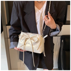 Detail of creamy white ballet-style bow shoulder bag with elegant silver chain strap
