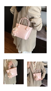Detail of light pink leather bucket bag featuring round studs and cute teddy bear charm