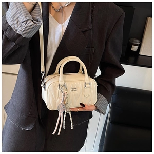 Close-up of quilted cream mini boston bag with sporty tennis racket and knot pendant