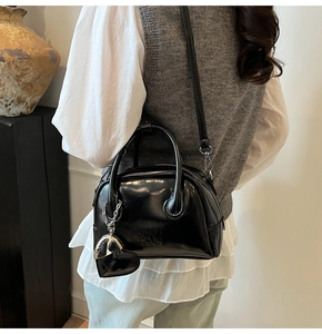 Detail of vintage black bowling bag with embossed letters and heart charm worn by model