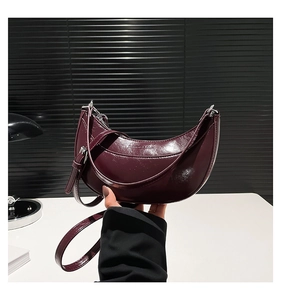 Détail du sac croissant rouge vin en cuir ciré brillant avec boucles en métal argenté