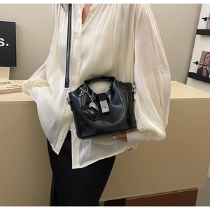 Détail du sac seau noir en cuir brillant avec breloque cœur et boucle argentée