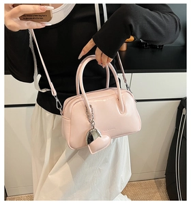 Detailed close-up of a pink patent leather Boston bag with heart pendant and metal buckle