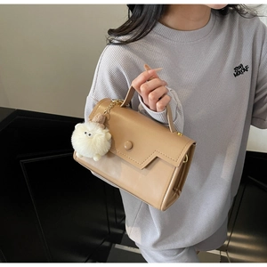Dettaglio borsa a mano cachi con patta geometrica e ciondolo decorativo in peluche