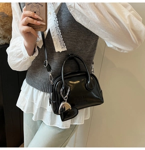 Top-down view of a glossy black patent leather bowling bag with a heart pendant