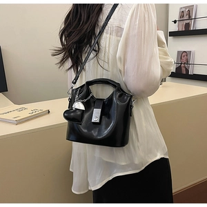 Détail du sac seau noir en cuir ciré avec boucle argentée et breloque coeur