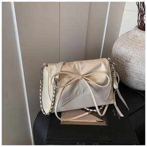 Detailed macro view of beige bow-knot handbag with chain strap and soft leather texture