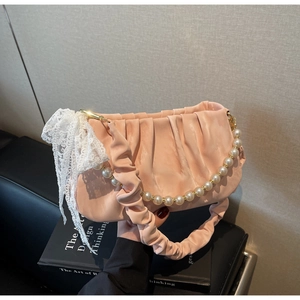 Detail of pink pleated underarm bag with pearl chain strap and lace bow accent