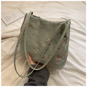 Close-up of light green tote bag with traditional Chinese mountain and pine embroidery