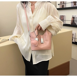 Gros plan du sac seau en cuir rose avec pendentif en forme de cœur et fermoir magnétique