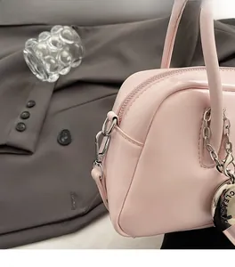 Detail of pink faux leather bag showing silver zipper and circular metal charm logo