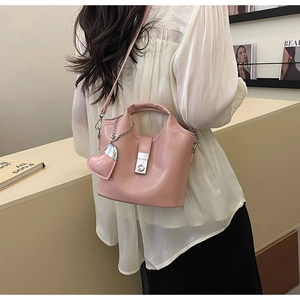 Détail du sac seau rose clair en cuir huilé avec breloque cœur et fermoir rotatif argenté