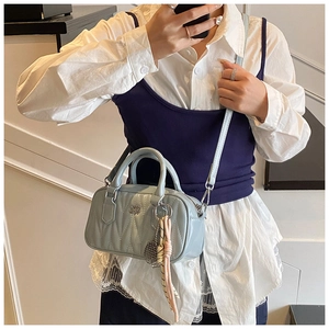 Close-up of light blue quilted mini pillow bag with tennis racket charm and shoulder strap
