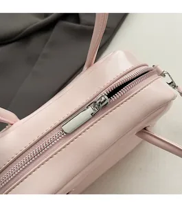 Close-up of smooth silver metal zipper on light pink leather minimalist handbag