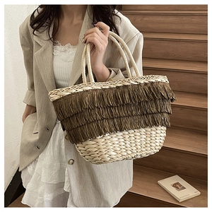 Détail du sac panier en paille beige avec trois rangées de franges marron et finitions tissées