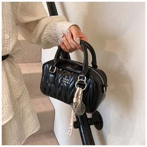 Detail view of black pleated handbag with diamond lattice and tennis racket charm