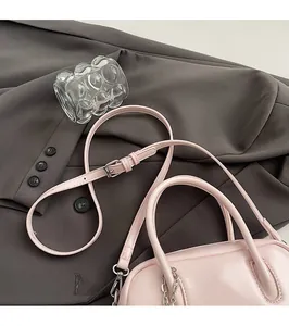 Detail of light pink crossbody bag with silver hardware and adjustable shoulder strap