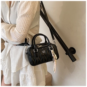 Detail of black pleated Boston bag showing letter logo and adjustable shoulder strap