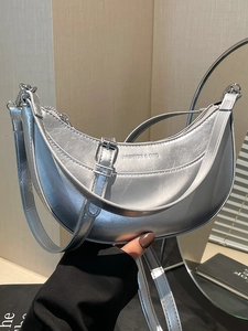 Sac à main demi-lune argenté métallisé avec bandoulière réglable porté par un mannequin