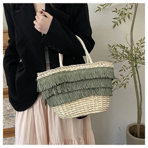Détail d'un sac cabas en paille bohème avec franges vertes et anses en corde tressée