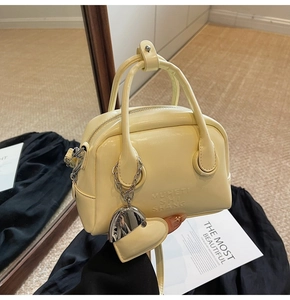 Detail of cream yellow bowling bag featuring smooth leather texture and heart metal charm