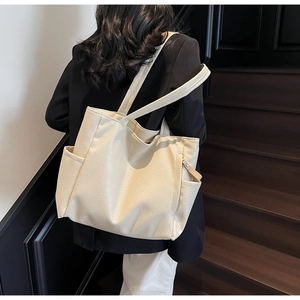 Detail of off-white tote bag with natural pleated texture and wide shoulder strap