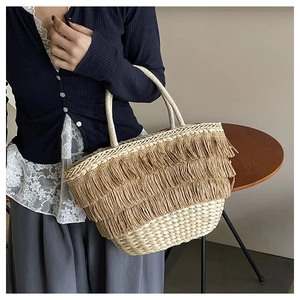 Détail d'un sac seau en paille tissé à la main avec trois couches de franges denses et chic