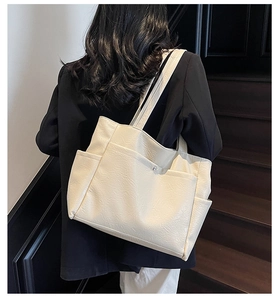 Detail of minimalist cream faux leather tote bag showing textured finish and pockets