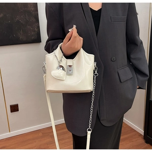 Détail du sac seau en cuir ciré brillant blanc cassé avec chaîne argentée et breloque miroir cœur