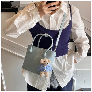 Light blue patent leather bucket bag with cute bear charm on a white shirt outfit
