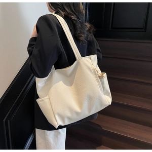 Detail view of cream white tote bag with textured soft leather and side pocket design