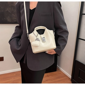 Détail d'un sac seau en cuir ciré crème avec pendentif en cœur et boucle en métal dorée