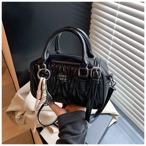 Detail of black quilted leather handbag featuring metal logo and tennis racket charm