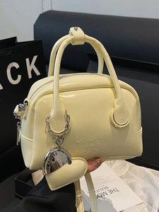 Pale yellow matte leather Boston bag with embossed logo and heart-shaped metal chain charm
