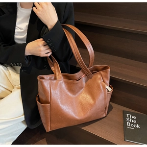 Close-up of brown faux leather tote bag showing lychee grain texture and side pocket