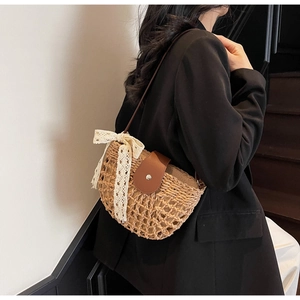 Detailansicht der Strohtasche mit Spitzenschleife und Lederriemen an einem Modell