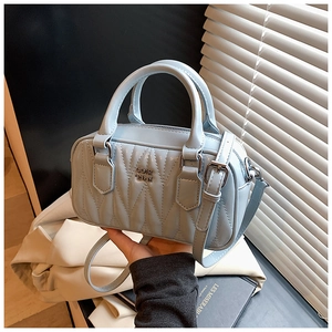 Detail of light blue quilted Boston bag with V-shaped stitching and metal logo