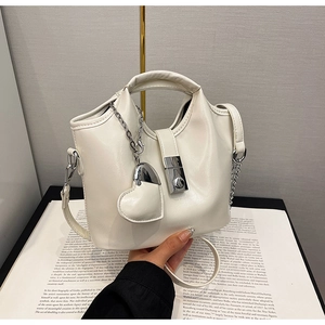 Détail du sac seau blanc crème avec boucle argentée et pendentif cœur sur un magazine