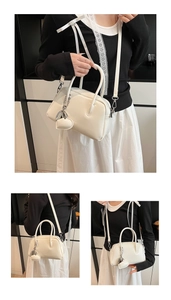 Detail view of white glossy leather bowling bag with silver heart charm and strap