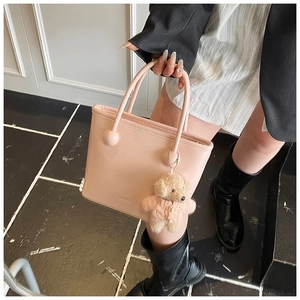 Detail of pink patent leather bucket bag with ball accents and plush bear charm decoration