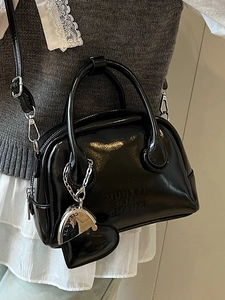 Chic black glossy bowling bag with round handles and adjustable strap for women