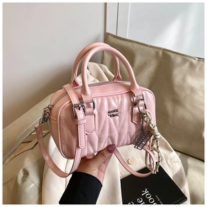 Detailed macro view of pink quilted leather Boston bag with metallic logo and knot charm