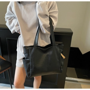 Close-up of black tote bag with lychee texture leather and side pockets detail