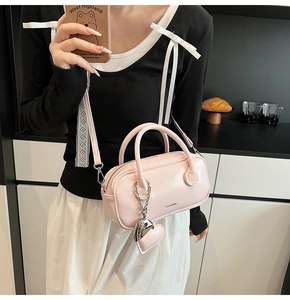 Photo lifestyle d'un sac oreiller rose avec breloque cœur et logo CLEARY sur un modèle